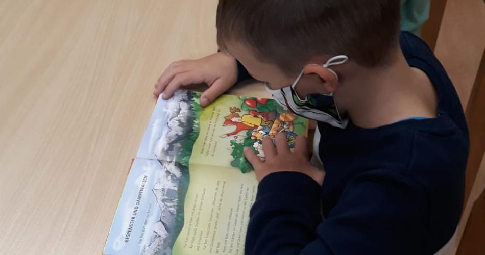 Kind lesen ein Buch und tragen einen Mund-Nasen-Schutz