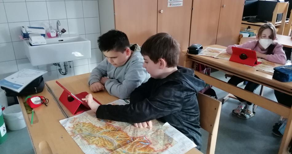 Kinder arbeiten mit Tablet und Landkarte