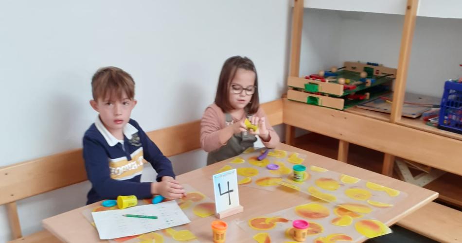Kinder formen den Buchstaben aus Knetmasse
