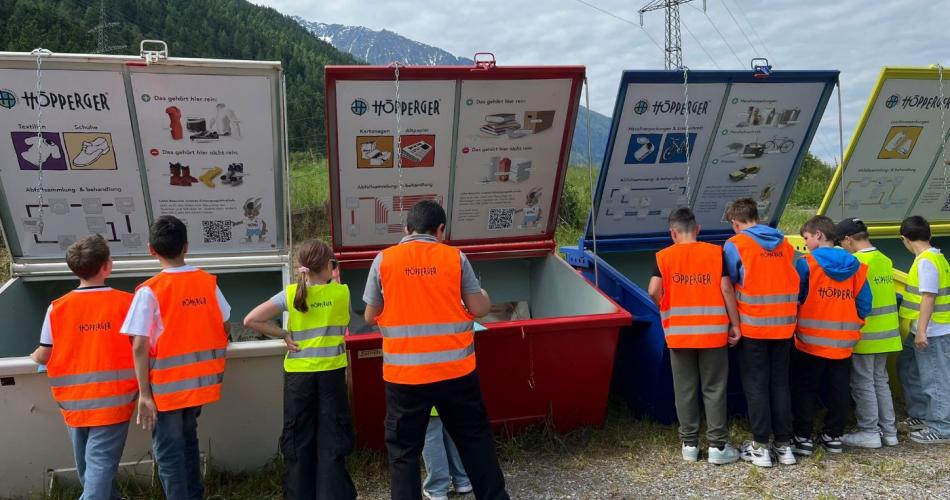 Kinder stehen vor verschieden farbigen Containern