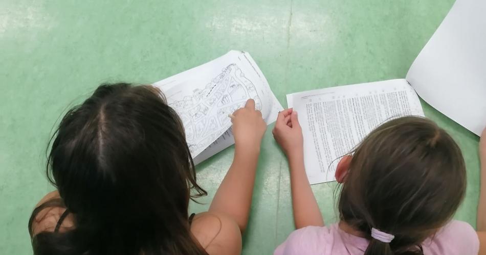 Kinder liegen am Boden und bearbeiten einen Lesetext