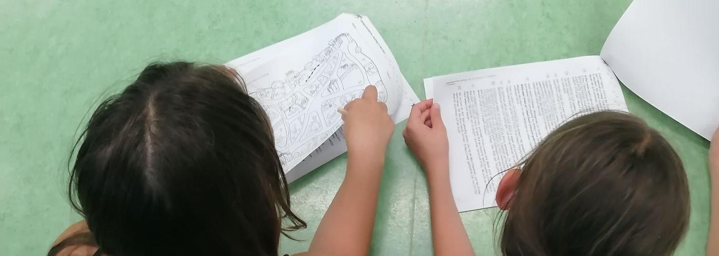 Kinder liegen am Boden und bearbeiten einen Lesetext