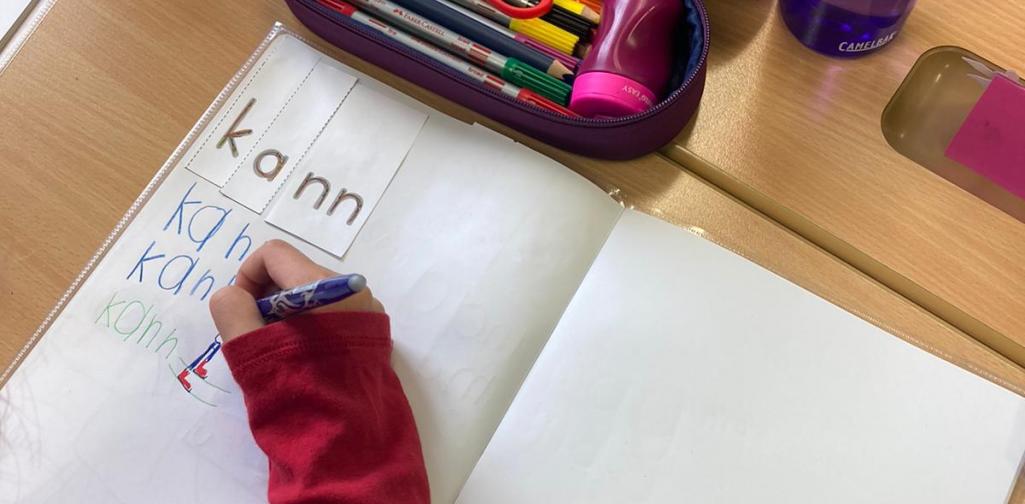 Wortzauberei 5 Heftseite, Arm eines Schülers der gerade schreibt