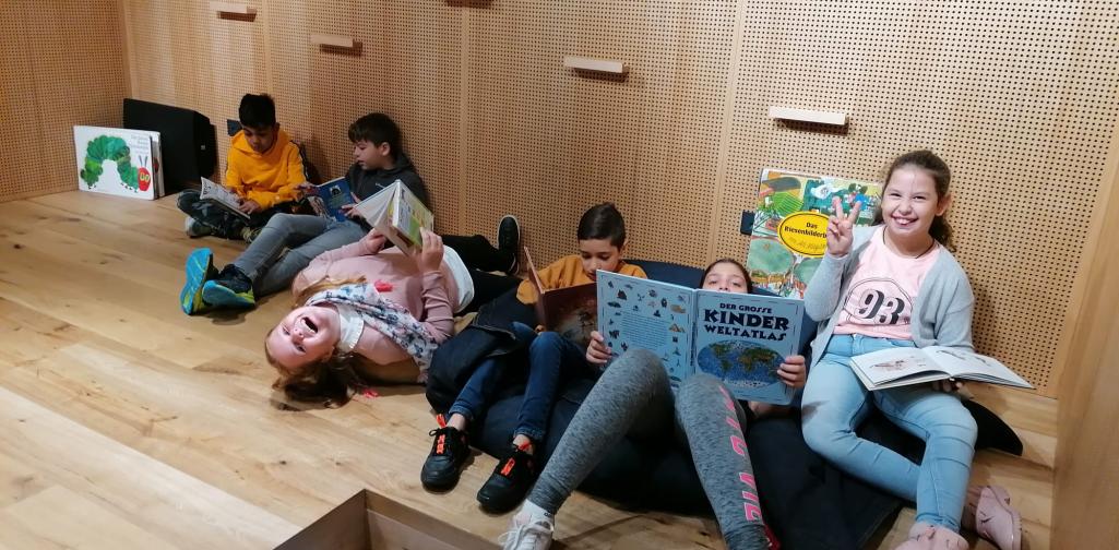 Kinder sitzen auf der Bühne und lesen Bücher