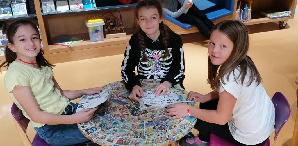 Kinder sitzen beim Tisch und lesen Bücher