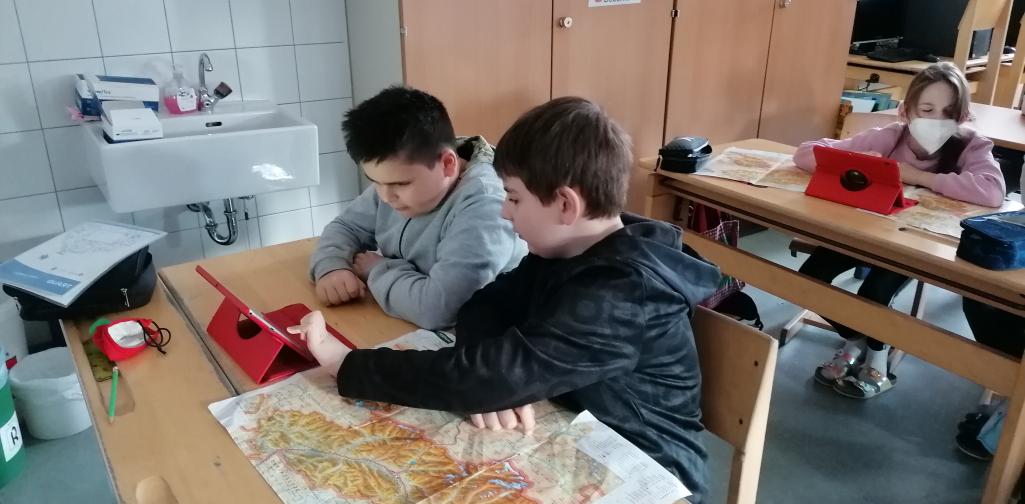 Kinder arbeiten mit Tablet und Landkarte
