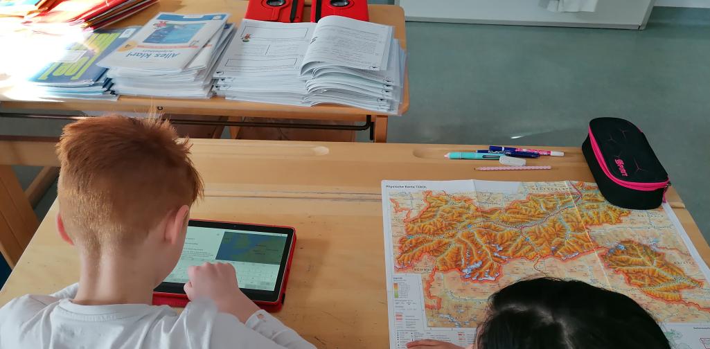 Kinder arbeiten mit Tablet und Landkarte