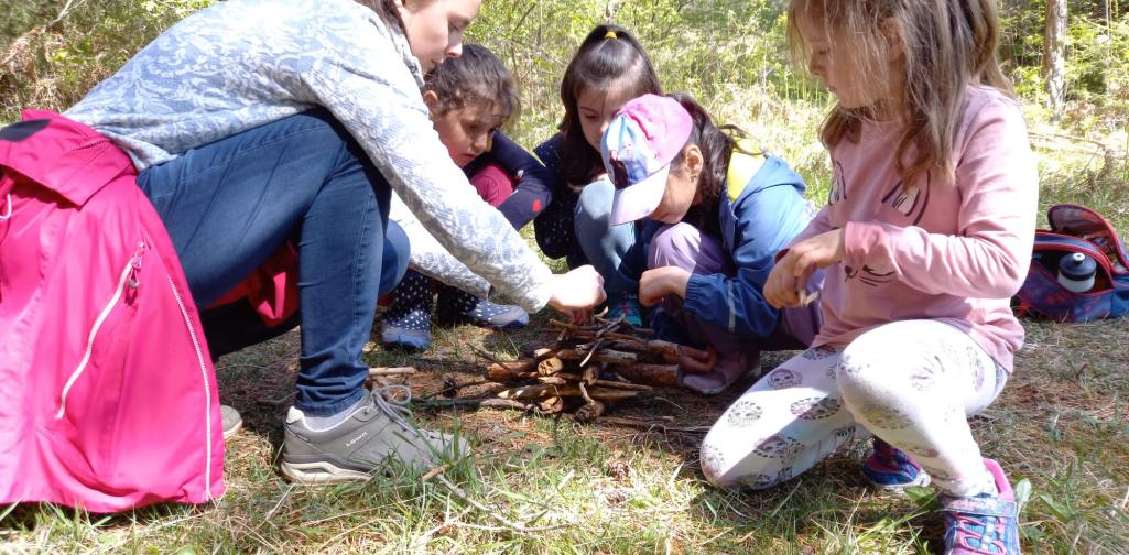 Kinder und Lehrperson bauen einen Turm aus Naturmaterialien