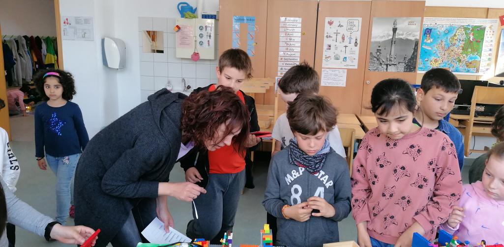 Kinder und eine Lehrerin sehen sich das LEGO Modell an