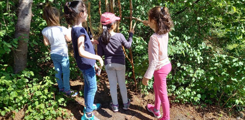 Kinder bauen eine Hütte aus Holzstöcken