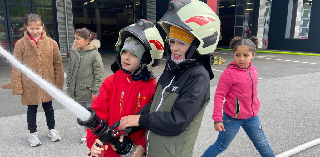 Kinder probieren den Löschschlauch aus