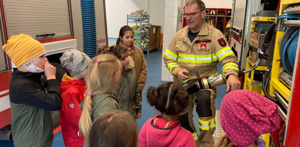 Kindern wird die Ausrüstung eines Feuerwehrautos erklärt