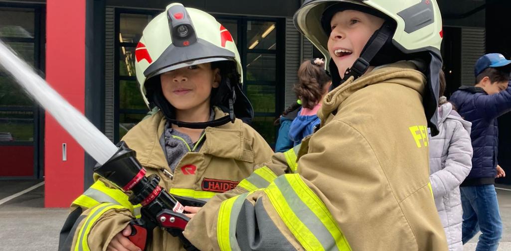 Kinder probieren den Löschschlauch aus