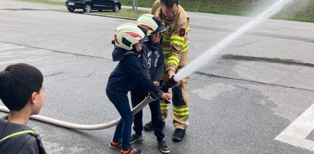 Kinder probiren den Löschschlauch aus