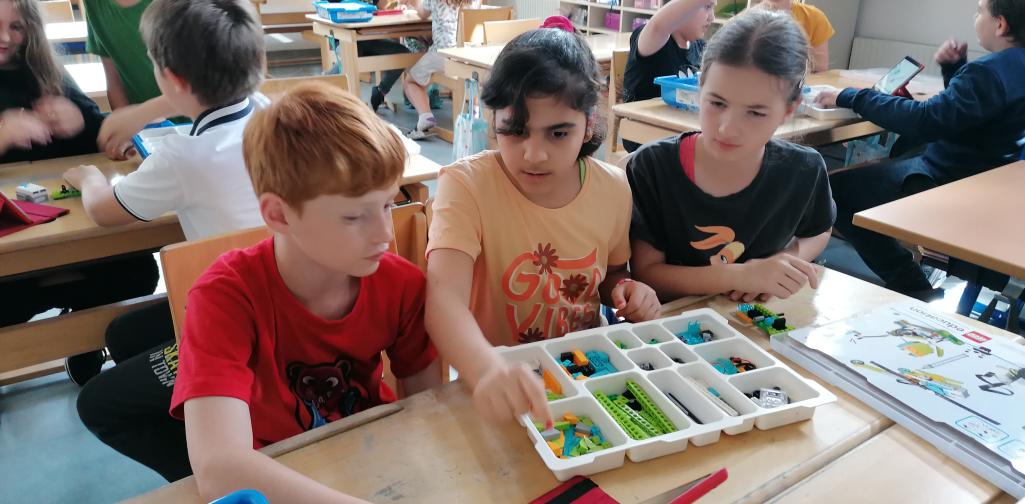 Kinder arbeiten mit LEGO und programmieren diesen am Tablet