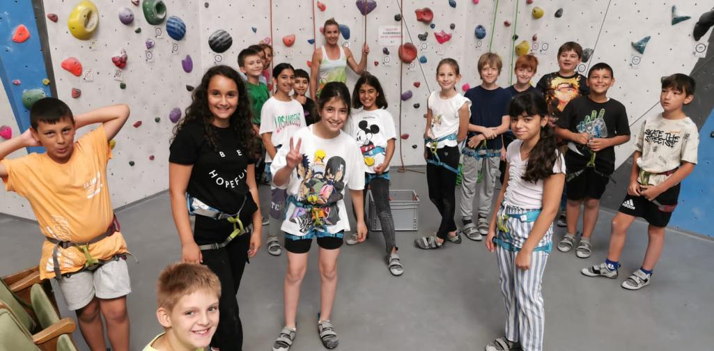 Kinder stehen vor der Kletterwand und freuen sich aufs Klettern