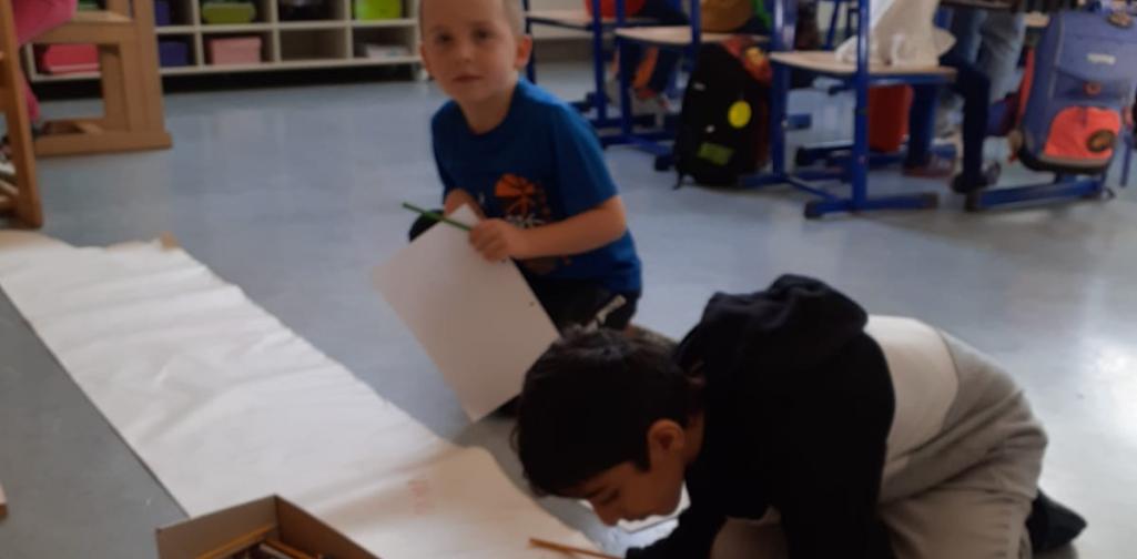 Kinder schreiben den Buchstaben auf Plakatpapier