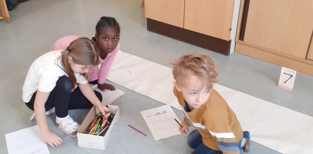 Kinder fahren den Buchstaben auf Plakatpapier nach