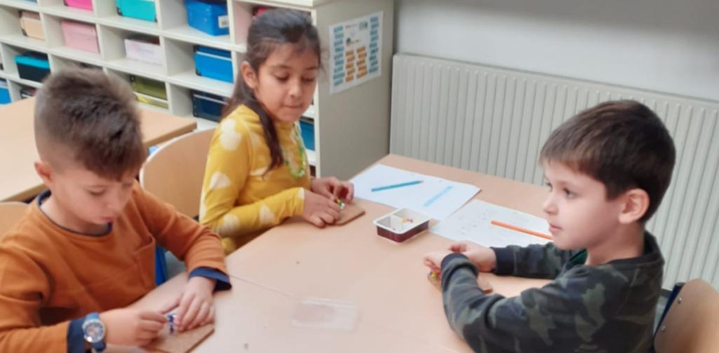 Kinder stecken den Buchstaben mit Stecknadeln nach