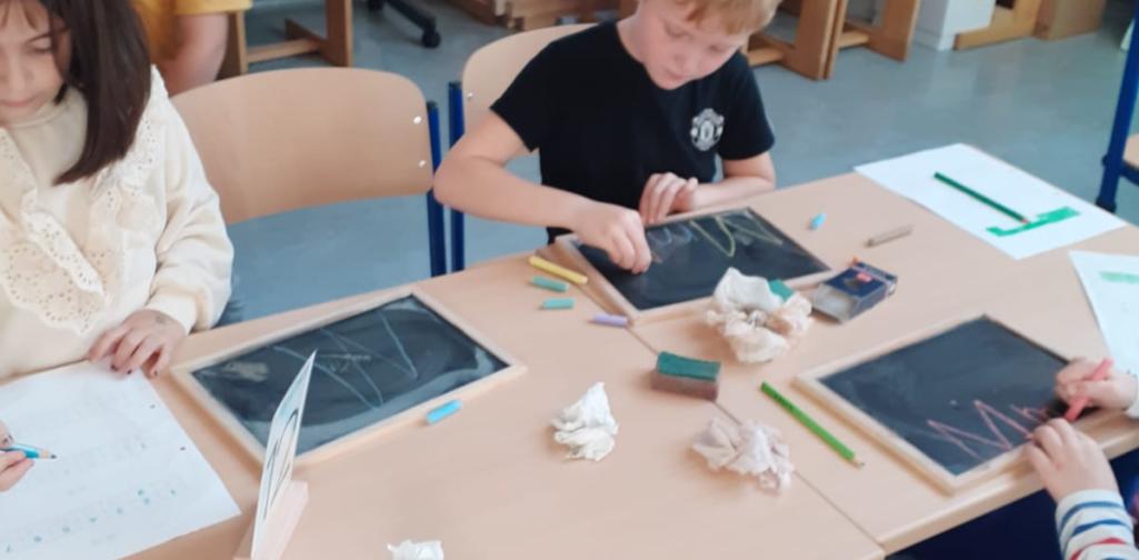 Kinder schreiben den Buchstaben auf kleinen Schiefertafeln