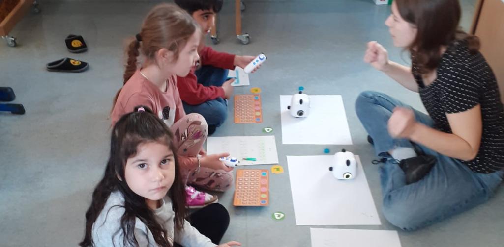 Kinder programmieren die TinyRobots, damit sie den Buchstaben nachfahren