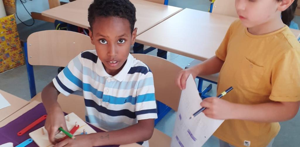 Kinder bauen den Buchstaben mit Puzzleteilen nach