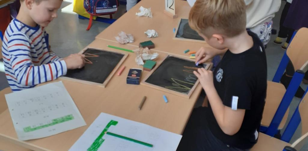 Kinder schreiben auf der Schiefertafel