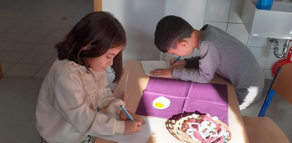 Kinder formen den Buchstaben mit Wollschnüren