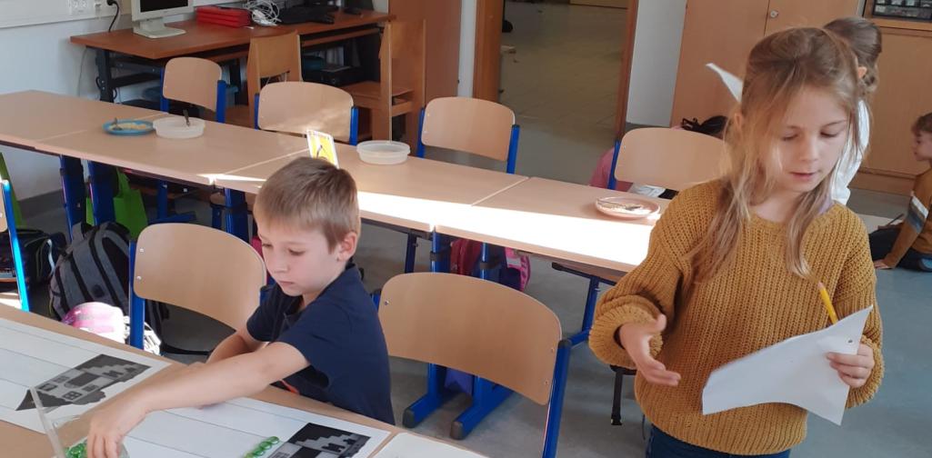 Kinder legen den Buchstaben mit Muggelsteinen nach