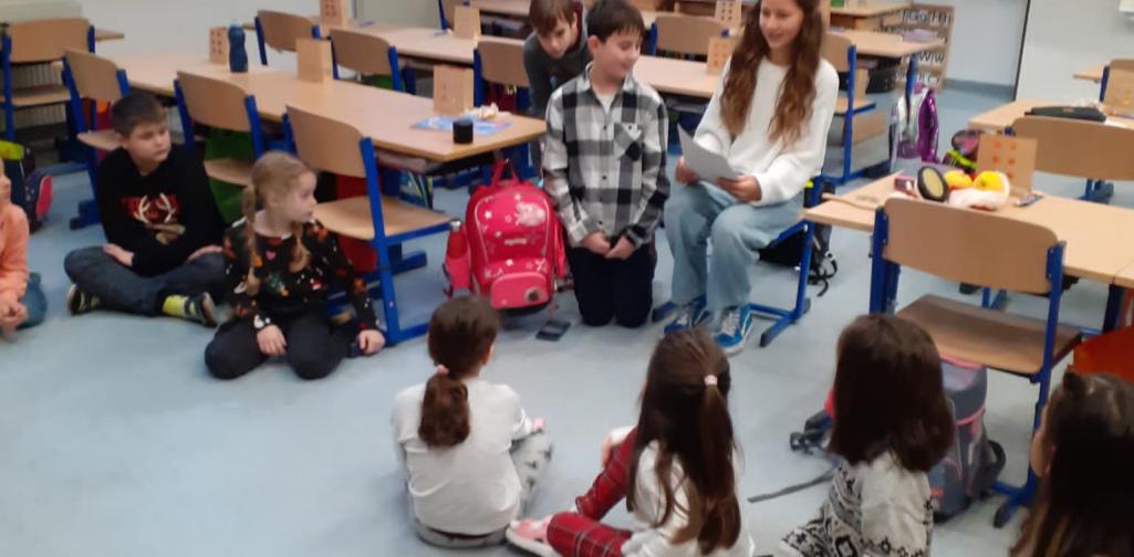 Kinder sitzen im Kreis, Mittelschüler lesen vor