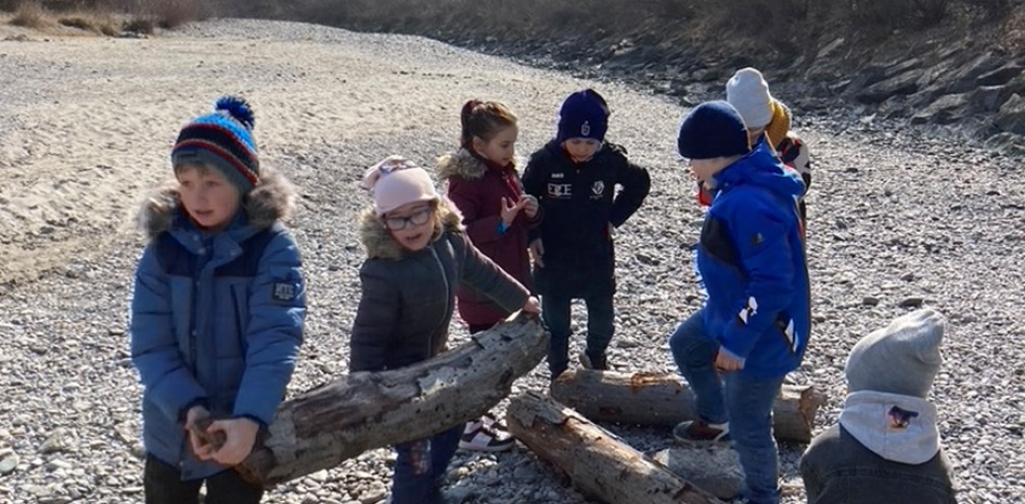 Kinder tragen gemeinsam einen Holzstamm