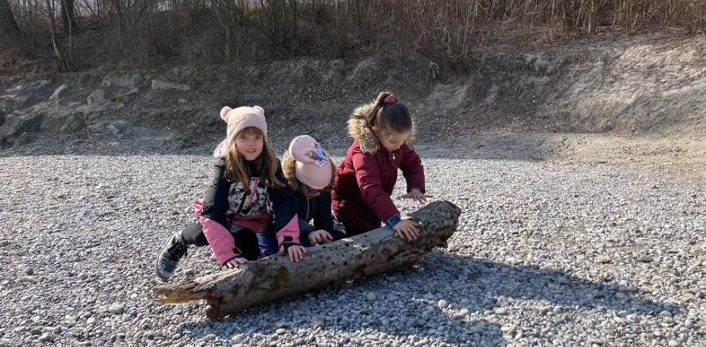 Kinder rollen einen Holzstamm