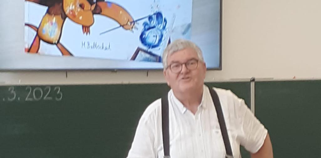 Vorlesetag 3 Der stolze Vorlesepate steht mit seinem Buch vor der Tafel.