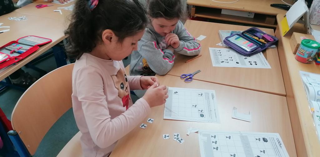 digitale Grundbildung 4 Kinder schneiden die Karten für das Arbeitsblatt aus