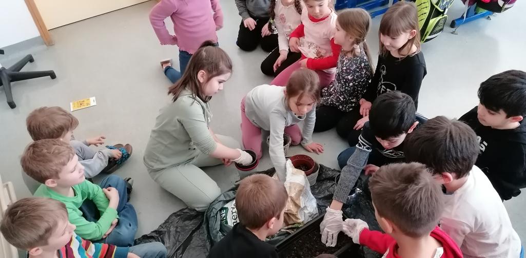 Blumen pflanzen 3 Kinder befüllen die Töpfe mit Erde