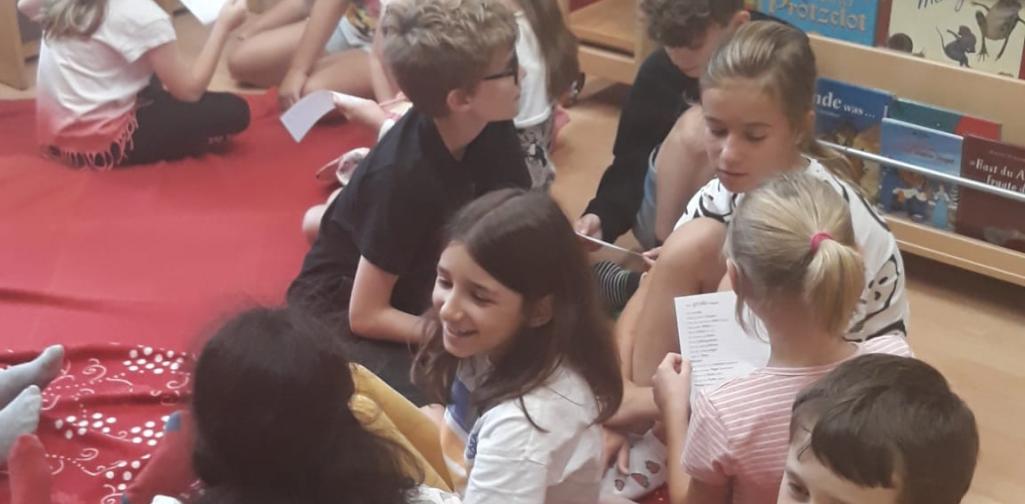 Vorlesetag 3 Kinder sitzen in der Bücherei im Kreis