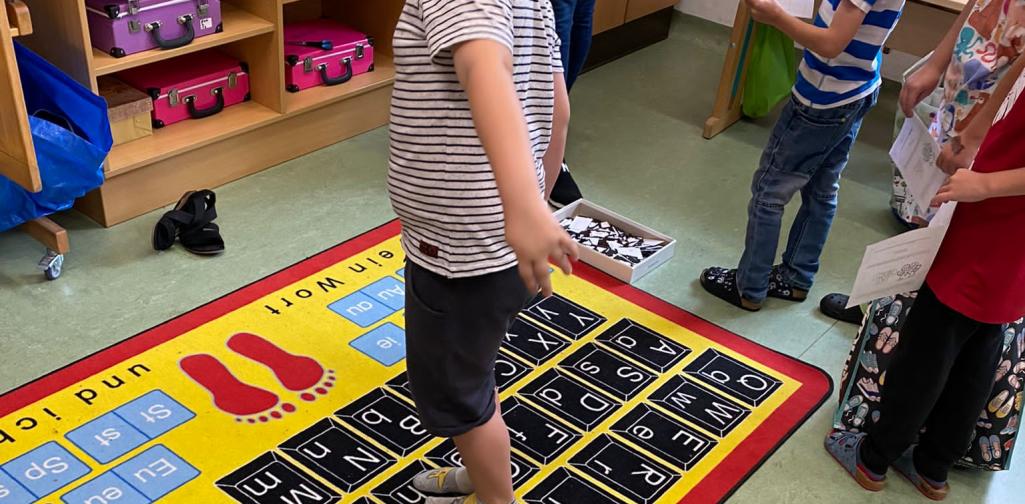 Kinder springen Wörter am Buchstabenteppich