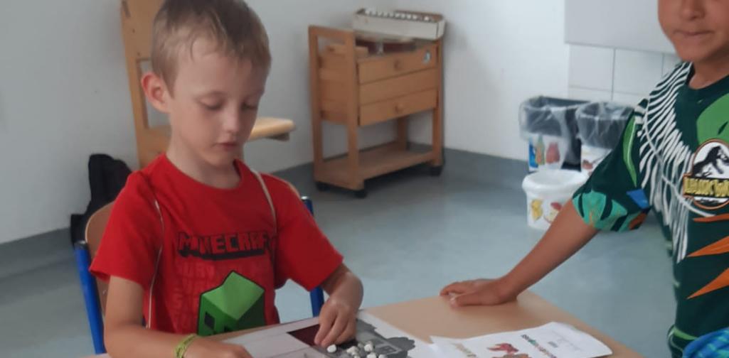 Kinder legen Buchstaben mit Steinen