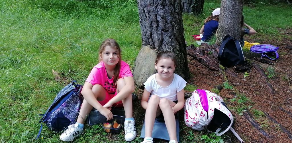 Wandertag 8 Kinder sitzen bei einem Baumstamm