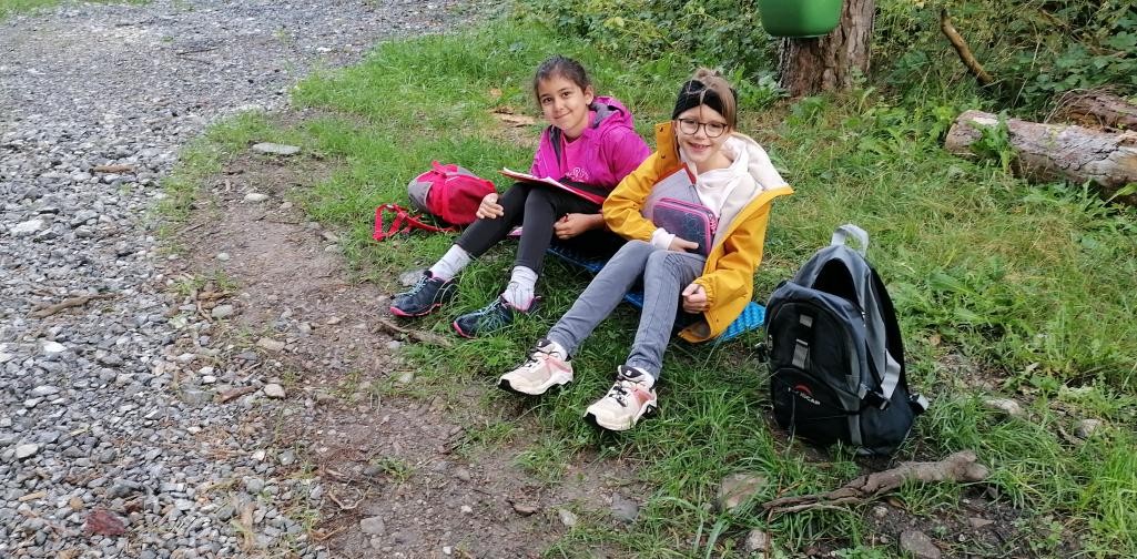 Schule im Wald 11 zwei Mädchen arbeiten im Wald an ihren Schulaufgaben