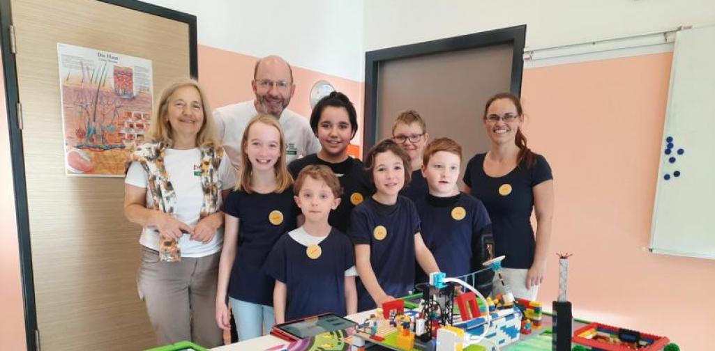 FLL 04 Gruppenfoto Kinder mit Lehrperson und Jury hinter dem Modell