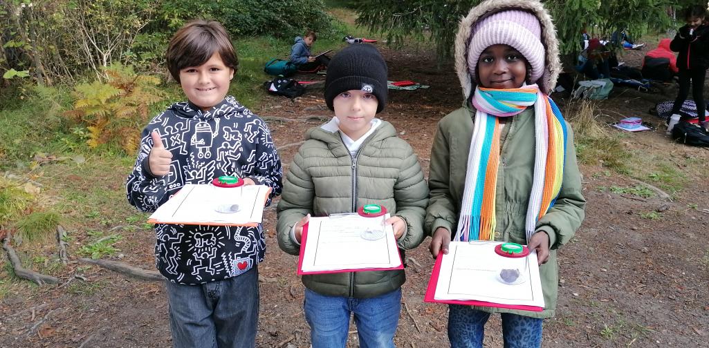 Wald 9 Kinder mit Klemmbrett und Becherlupe