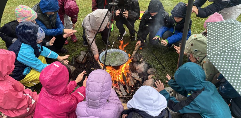 Die Kinder wärmen sich an der Feuerstelle und kochen einen Tee.