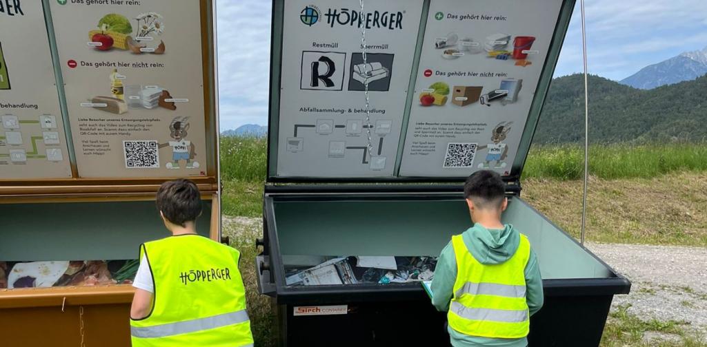 Kinder stehen vor zwei Müllcontainern