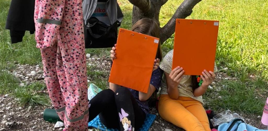 Kinder sitzen vor einem Baum