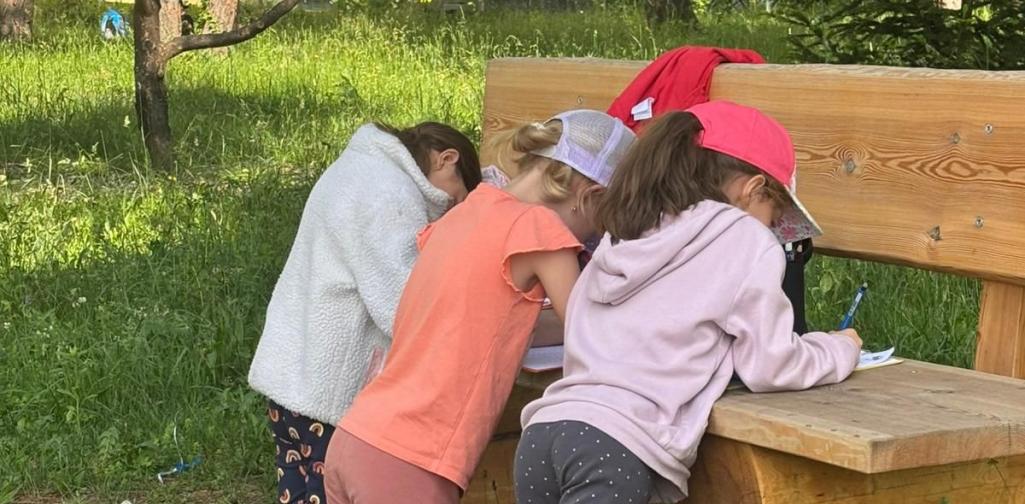 Kinder lösen ihre Aufgaben auf einer Bank