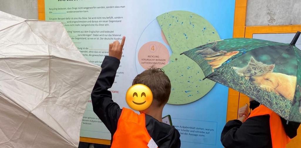 Kinder stehen vor einem Plakat zum Thema Recycling