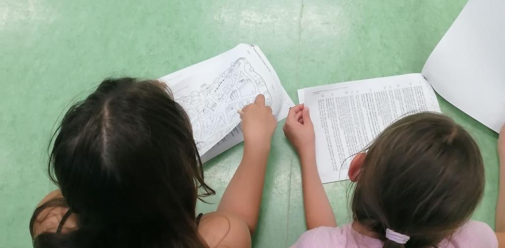 Kinder liegen am Boden und bearbeiten einen Lesetext