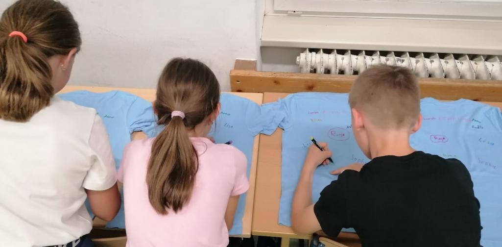 Kinder unterschreiben auf blauen T-Shirts